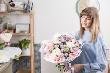 Güneşli bahar sabahı. Karışık buket bir güzel lüks tutan genç mutlu kadın. bir çiçek mağazası, çiçekçi iş