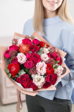 Sunny spring morning. Young happy woman holding a beautiful luxury bouquet of mixed flowers. the work of the florist at a flower shop. vertical photo clipart
