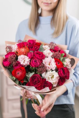 Güneşli bahar sabahı. Karışık buket bir güzel lüks tutan genç mutlu kadın. Çiçekçi Çiçek dükkanında çalışır. dikey fotoğraf