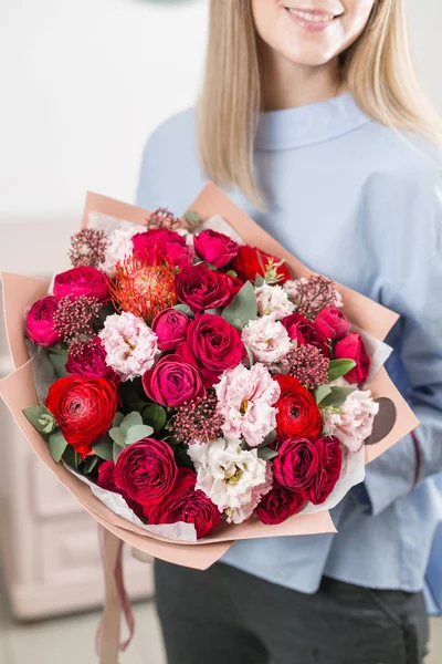 Manhã de primavera ensolarada. Jovem mulher feliz segurando um belo buquê de luxo de flores mistas. o trabalho da florista em uma loja de flores. foto vertical — Fotografia de Stock