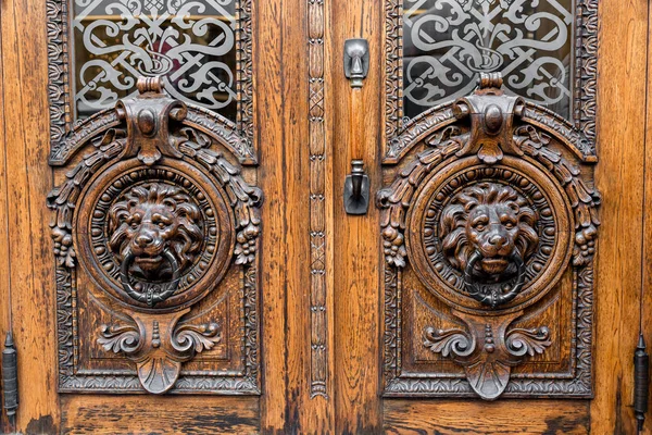 Vecchia porta di legno. Due grandi teste di leone sul davanti. porta d'epoca bussare . — Foto Stock