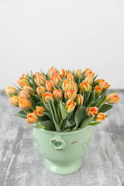 Tulips of orange color in green vase. Big buds of multicoloured tulips. Floral natural backdrop. Bicolour tulips filled picture. Unusual flowers, unlike the others. Shallow focus. — Stock Photo, Image