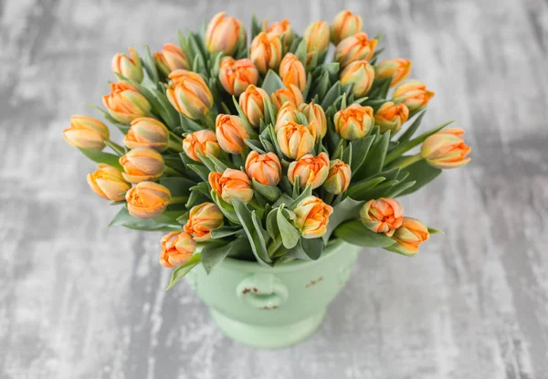 Orangefarbene Tulpen in grüner Vase. große Knospen von bunten Tulpen. Florale Naturkulisse. Zweifarbige Tulpen füllten das Bild. ungewöhnliche Blumen, im Gegensatz zu den anderen. Oberflächlicher Fokus. — Stockfoto