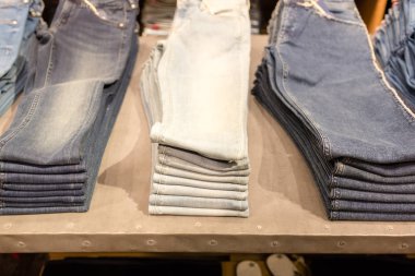 Mavi jeans bir dükkanda yığını. Satılık alışveriş arka plan teması. Elbise dükkanı askı