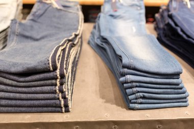 Mavi jeans bir dükkanda yığını. Satılık alışveriş arka plan teması. Elbise dükkanı askı