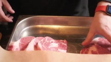 Şef et keser. Karanlık masada metal plaka üzerinde taze çiğ et. Seçici odak.