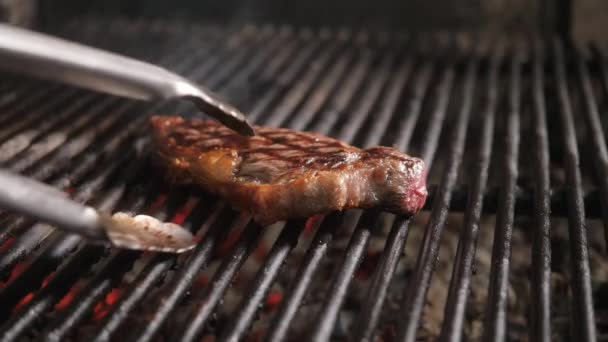 Fritar o bife no churrasco. Churrasco típico argentino ou asado. Queima de madeira na grelha e carvão quente vermelho . — Vídeo de Stock