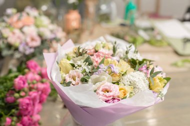 ahşap masa üzerinde bir vazoda karışık çiçekler güzel buket. Çiçekçi Çiçek dükkanında çalışır. Küçük bir aile şirketi