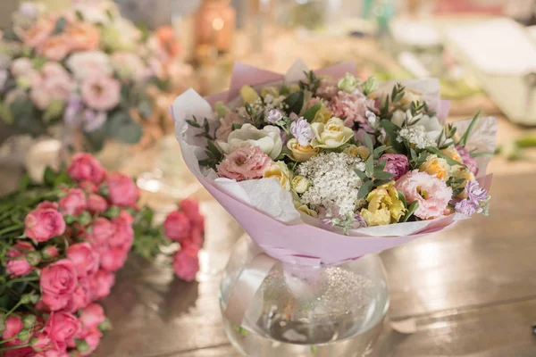 ahşap masa üzerinde bir vazoda karışık çiçekler güzel buket. Çiçekçi Çiçek dükkanında çalışır. Küçük bir aile şirketi