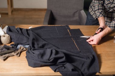 Kesme karanlık yün kumaş. çizgi deseni. Bir terzi çalışma ve atölyede bir dikiş makinesi kullanarak genç adam.