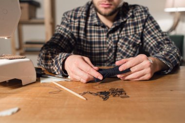 bir iğne ve iplik el ile. Bir terzi çalışan ve bir dikiş makinesi bir tekstil Studio'yu kullanarak iyi görünümlü genç adam.