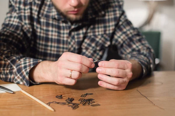 Med en nål och tråd i hand. Bra snygg ung man arbeta som skräddare och använda en symaskin i en Textilkammare. — Stockfoto