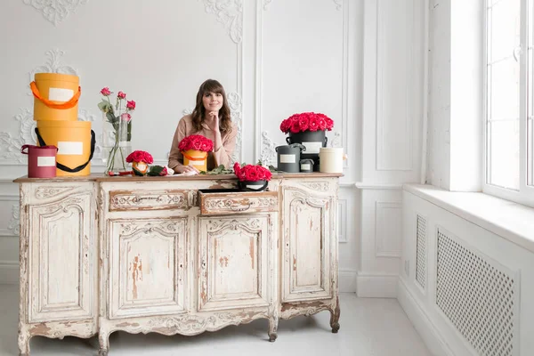 Jeune fleuriste organisant des plantes dans un magasin de fleurs. Les gens, les affaires, la vente et le concept de floristique. Bouquet de roses rouges — Photo