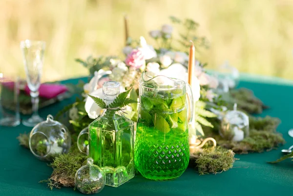 Decoración del bosque. Lanzador de limonada con lima, menta y hielo en la mesa — Foto de Stock