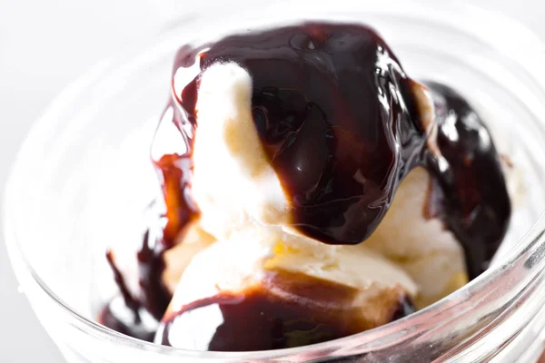 Sorvete de baunilha com xarope de chocolate sobre fundo branco. Colheres de sorvete de baunilha na tigela de óculos . — Fotografia de Stock