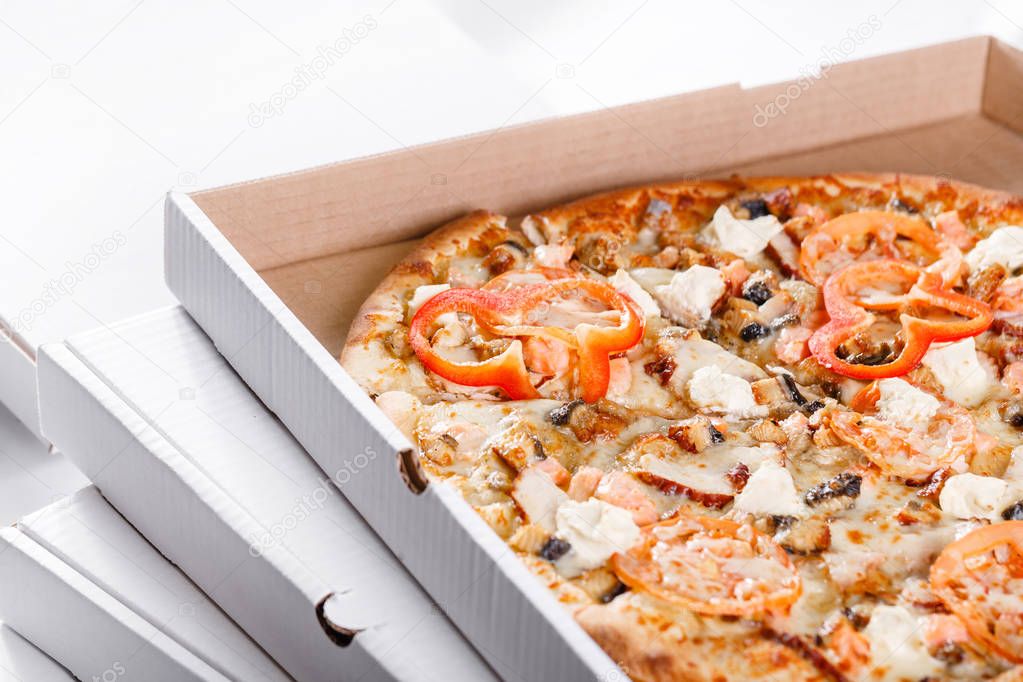 Pizza box delivery concept. Open box with hot tasty italian sliced pizza with salmon, eel, seafood, olives, basil, tomato, mushrooms.