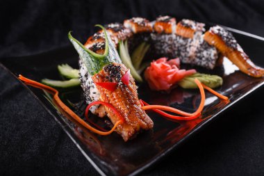 Suşi Ejder yılan balığı, salatalık ve avokado siyah bir arka plan ile. Japon yemekleri, lezzetli yemek öğle yemeği için
