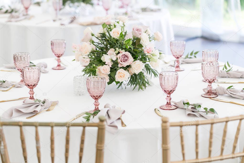 Beautiful table setting with crockery and flowers for a party, wedding reception or other festive event. Glassware and cutlery for catered event dinner.