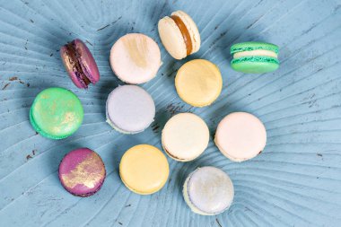 Yakın çekim renkli Fransızca veya İtalyanca macaron mavi ahşap masa üzerinde. Macarons Fransız tatlı çay veya kahve ile servis var. duvar kağıdı, yatay fotoğraf