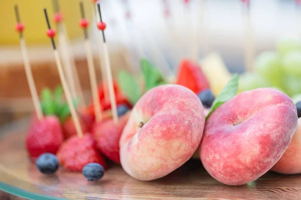 Prato de madeira com frutas fatiadas e bagas em uma mesa de buffet. Verão festa ao ar livre. Fotografia horizontal — Fotografia de Stock