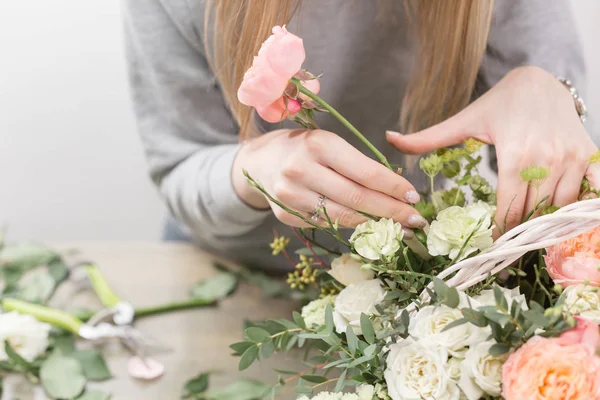 Primer plano manos florista femenina. El taller floral - la mujer que hace la composición hermosa de flores el ramo en la cesta de mimbre. Concepto floristería — Foto de Stock