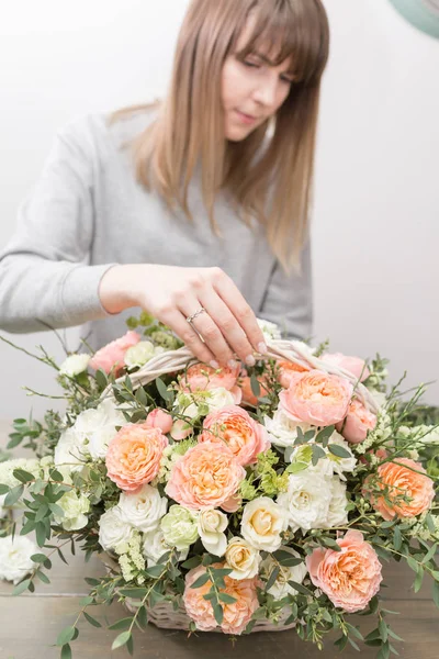 Primer plano manos florista femenina. El taller floral - la mujer que hace la composición hermosa de flores el ramo en la cesta de mimbre. Concepto floristería — Foto de Stock