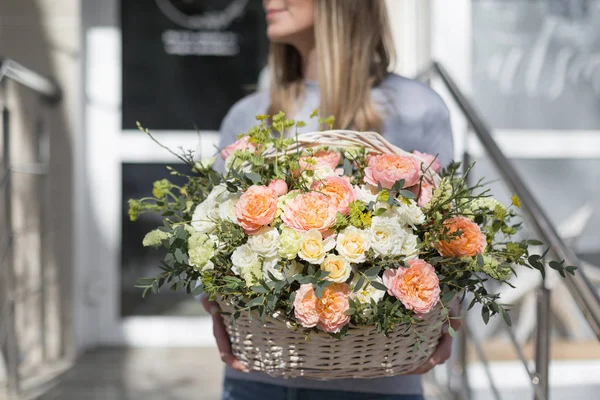 Cesta de mimbre con flores en manos de mujer. Hermosa composición floral. Concepto floristería. Primavera colores — Foto de Stock