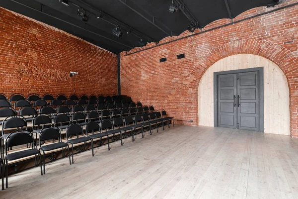 Loft style. Hall with black chairs for webinars and conferences. A huge room with large Windows, surrounded by brickwork, and parquet floors. For film and theatre productions — Stock Photo, Image