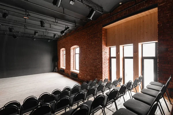 Loft style. Hall with black chairs for webinars and conferences. A huge room with large Windows, surrounded by brickwork, and parquet floors. For film and theatre productions — Stock Photo, Image