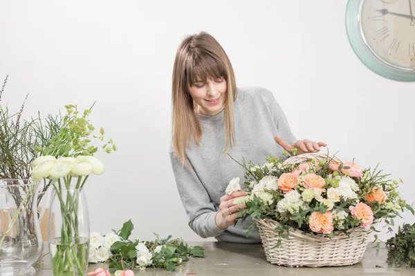 Florista feminina sorridente. Oficina floral - mulher fazendo uma bela composição de flores um buquê em uma cesta de vime. Conceito de floricultura — Fotografia de Stock