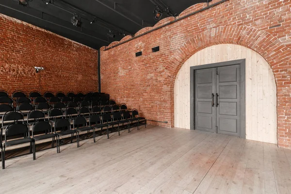 Large door. Loft style. Hall with black chairs for webinars and conferences. A huge room with large Windows, surrounded by brickwork, and parquet floors. For film and theatre productions — Stock Photo, Image