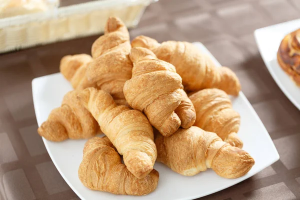Färska croissanter på vit platta. Franska traditionella bakverk. Frukost i hotel smörgåsbord. — Stockfoto
