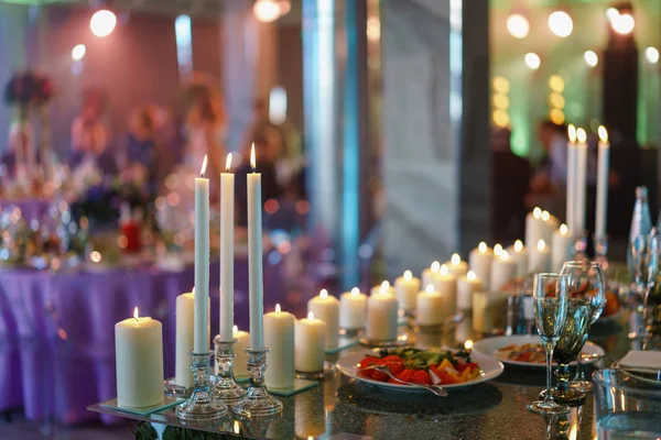 Vela encendida. Velas blancas en candelabros de vidrio están sobre mesas en la recepción de bodas de lujo en el restaurante. decoración elegante y adorno — Foto de Stock