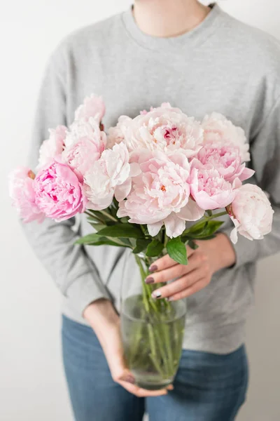 Милі і милі квіти півонії в жіночих руках... багатошарові пелюстки. Букет з блідо-рожевих півоній квіти світло-сірого кольору. Шпалери, вертикальне фото — стокове фото