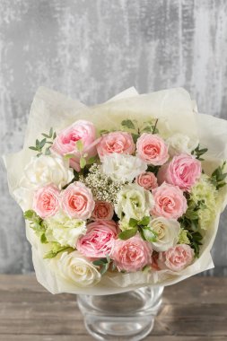 Yakın çekim güzel buket. Gri arka plan bahar çiçekleri. çiçekçi dükkanı. Ahşap masa. Dikey fotoğraf