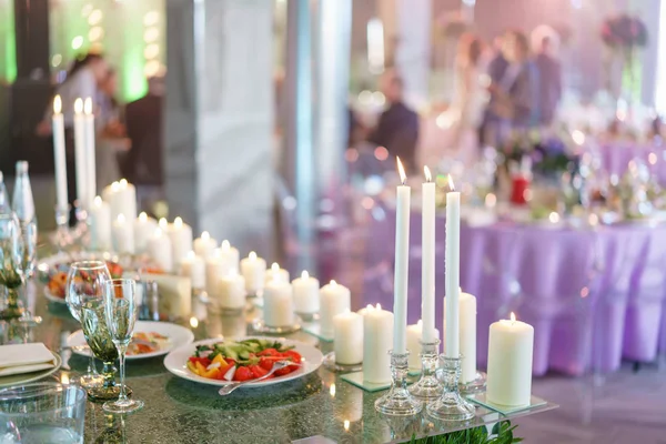 Burning candle. White candles on glass candlesticks stand on tables at luxury wedding reception in restaurant. stylish decor and adorning