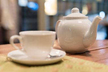 Sıcak çay bardağı kaşık beyaz tabak, Beyaz su ısıtıcısı, arka planda, Kahvaltı kavramı bulanık kafe ile