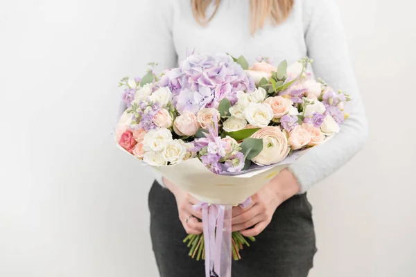 Ramo lila y ligero de hermosas flores en las manos de las mujeres. Concepto floristería. Colores de primavera. el trabajo de la floristería en una florería. Foto vertical — Foto de Stock