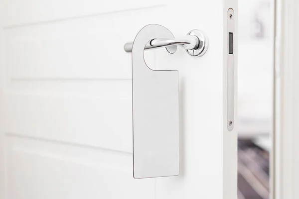 Door knob with empty label on a door handle for your text. Empty white flyer mockup hang on door handle. Leaflet design on entrance doorknob. Dont disturb sign. Hotel room clear hanger. blank