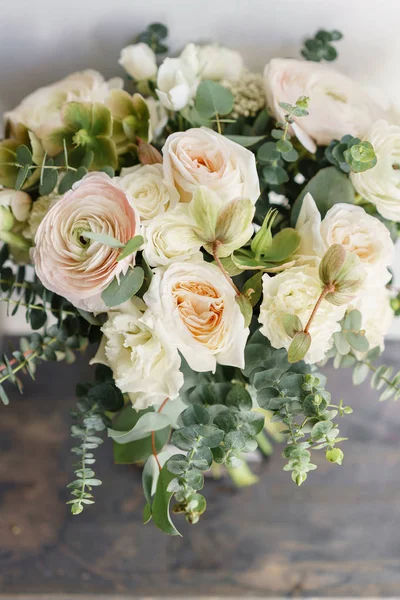 Wedding bouquet of white roses and buttercup on a wooden table. Lots of greenery, modern asymmetrical disheveled bridal bunch — Stock Photo, Image