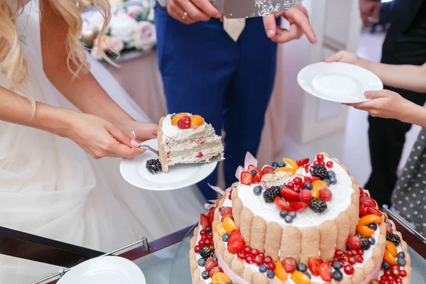 Bolo de casamento com bagas. Noiva e noivo cortam bolo doce no banquete no restaurante . — Fotografia de Stock