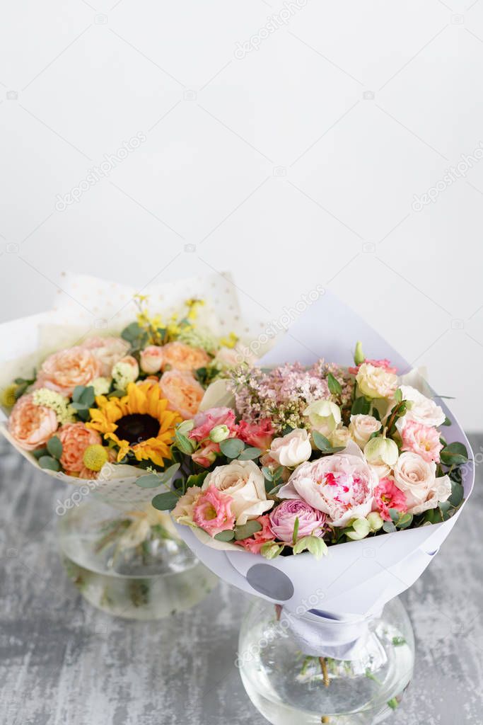 two bouquet of beautiful flowers on gray table. Floristry concept. Spring colors. the work of the florist at a flower shop. Vertical photo