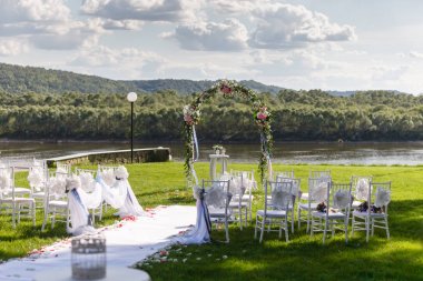 Nehir. Romantik düğün töreni. Şerit ve çiçeklerle bir yeşil çim üzerinde beyaz ahşap sandalyeler. Konuklar güzel Ofis koltukları