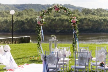 Nehir. Romantik düğün töreni. Şerit ve çiçeklerle bir yeşil çim üzerinde beyaz ahşap sandalyeler. Konuklar güzel Ofis koltukları