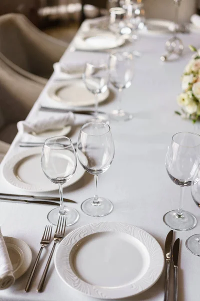 Tischdekoration im Restaurant, Gläser im Vordergrund. Luxus-Hochzeitsempfang. Blumengesteck auf dem Tisch im Restaurant. stilvolles Dekor und Dekoration. — Stockfoto