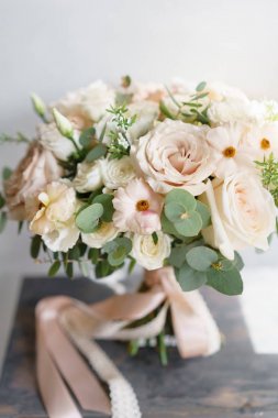 Beyaz güller sevdiceğim ahşap bir masa üzerinde bir buket düğün. Bir sürü yeşillik, asimetrik modern gelin grup darmadağınık.