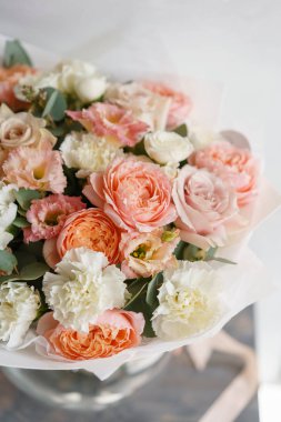pastel turuncu ve Pembe buket güzel ahşap masa üzerinde. Floristik kavramı. Bahar renkleri. Çiçekçi Çiçek dükkanında çalışır. Dikey fotoğraf