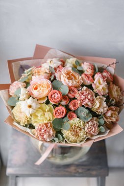 pastel turuncu ve Pembe buket güzel ahşap masa üzerinde. Floristik kavramı. Bahar renkleri. Çiçekçi Çiçek dükkanında çalışır. Dikey fotoğraf