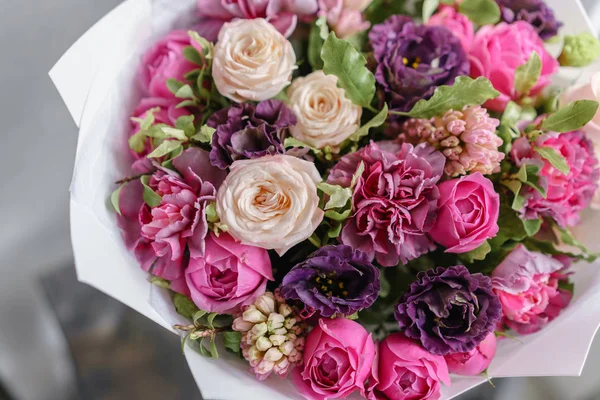 Bouquet viola e rosa di bellissimi fiori sul tavolo di legno. Concetto di fioritura. Colori primaverili. il lavoro del fioraio in un negozio di fiori. Foto verticale — Foto Stock