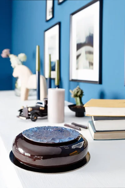 Πολυτελές στρογγυλό επιδόρπιο σοκολάτας, με ένα μπλε δίσκο σε μαύρο γάνωμα. Γενέθλια τούρτα με διακόσμηση μους. σε ένα ξύλινο τραπέζι — Φωτογραφία Αρχείου